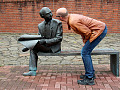 a man bending down to look closely at a sculpture on a bench